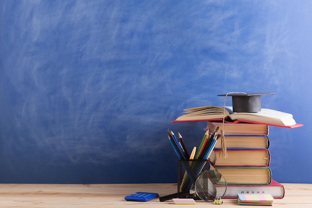 Libri concettuali di istruzione e scienze sulla scrivania dell'insegnante nella lavagna dell'auditorium sullo sfondo