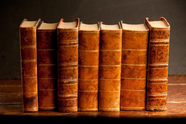 libri d'epoca sulla vecchia mensola in legno e sfondo scuro