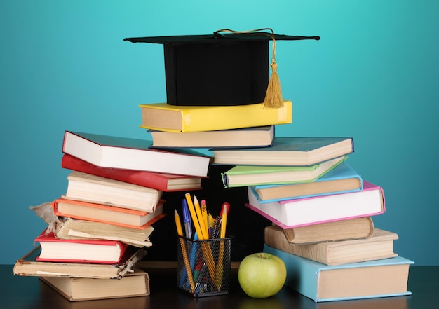 Libri e magister cap contro il consiglio scolastico sulla tavola di legno su sfondo blu