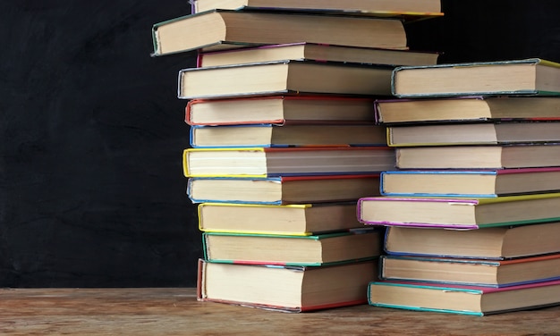 Libri in pile sul tavolo di una lavagna di scuola.