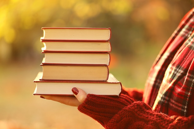 Libri per l'autunno. Lettura del libro d'autunno. Pila di libri nelle mani. Tempo d'autunno.