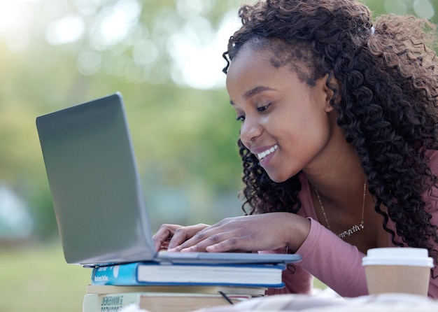 Libri per laptop e istruzione con una studentessa nera nel campus dell'università per studiare imparare o ricercare Computer internet e imparare con una studentessa universitaria che studia fuori su un campo