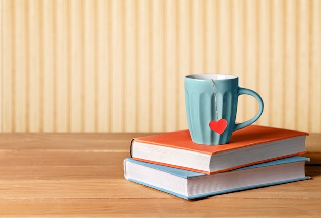 Libri, tazza da tè con cuore sul tavolo