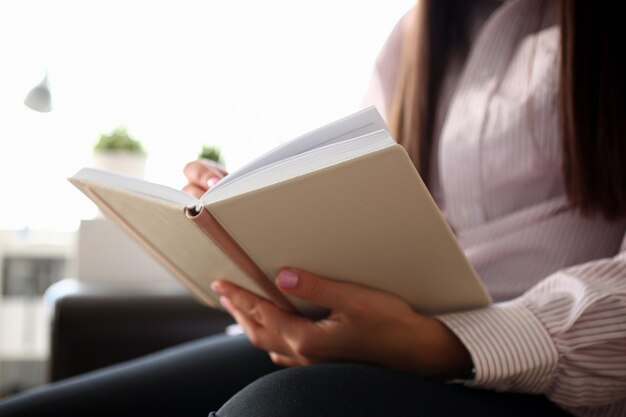 Libro aperto della tenuta femminile della mano che si trova al primo piano dello strato.