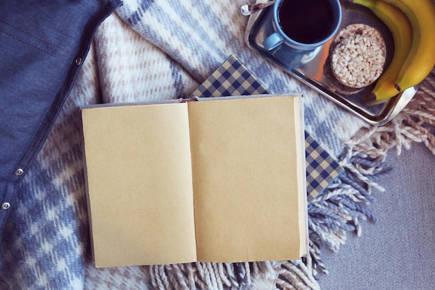 Libro aperto plaid e caffè sul divano Vista dall'alto