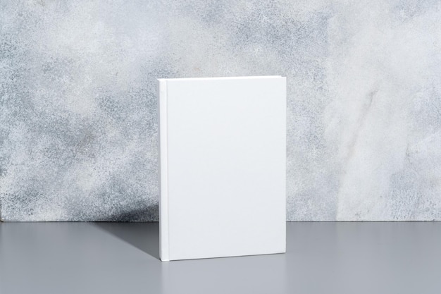 Libro bianco a copertina rigida su sfondo grigio con ombre