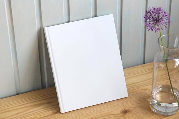 Libro bianco appoggiato su uno scaffale di legno con un fiore decorativo