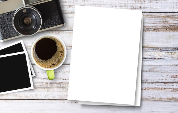 Libro bianco e tazza di caffè e macchina fotografica sul fondo della tavola di legno