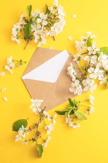 Libro bianco in bianco in busta e fiori intorno ad esso su sfondo di colore di carta