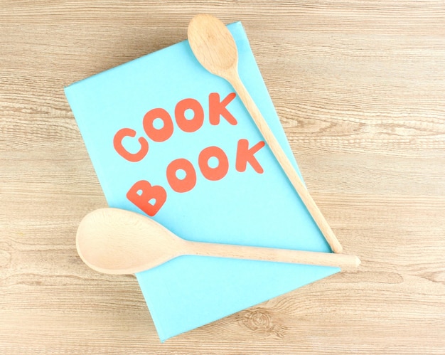 Libro di cucina e utensili da cucina su sfondo di legno