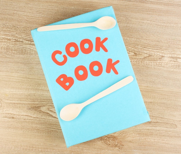 Libro di cucina e utensili da cucina su sfondo di legno