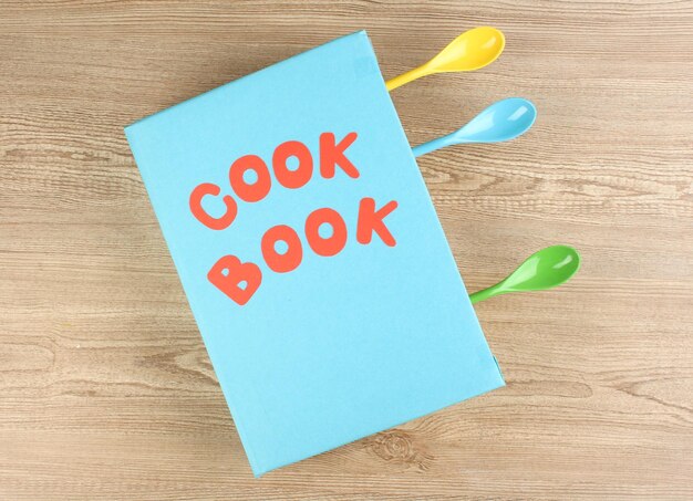 Libro di cucina e utensili da cucina su sfondo di legno