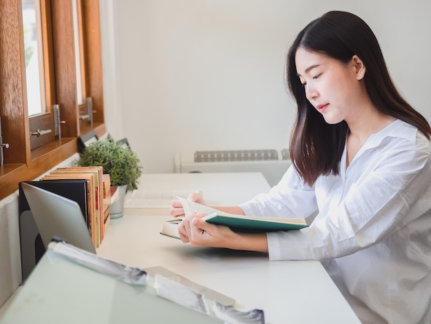 Libro di lettura asiatico della donna in stanza di funzionamento