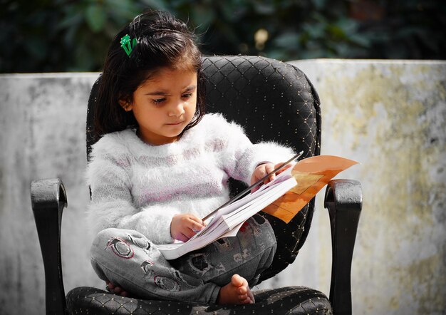 Libro di lettura bambino carino seduto sulla sedia