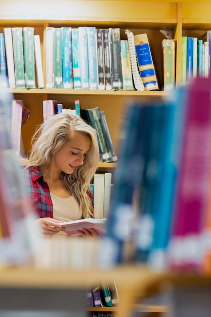 Libro di lettura degli studenti in mezzo a scaffali in biblioteca