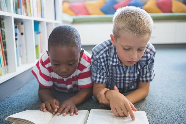 Libro di lettura dei bambini della scuola in biblioteca