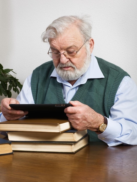 Libro di lettura dell'uomo anziano sulla tavoletta digitale