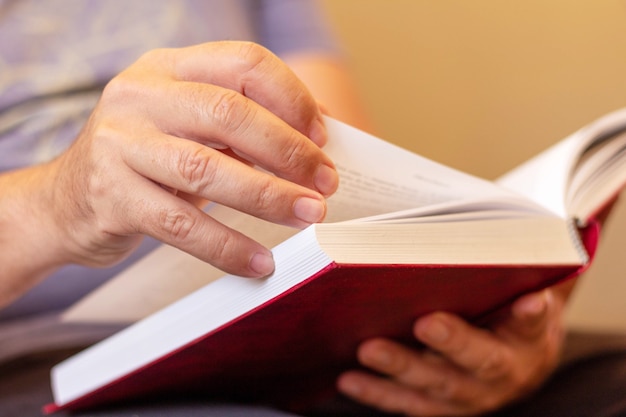 Libro di lettura dell'uomo con copertina rossa. Messa a fuoco selettiva.