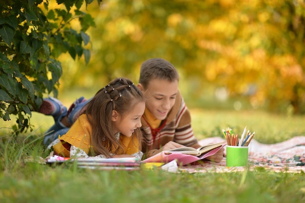 Libro di lettura della bambina e del ragazzo all'aperto