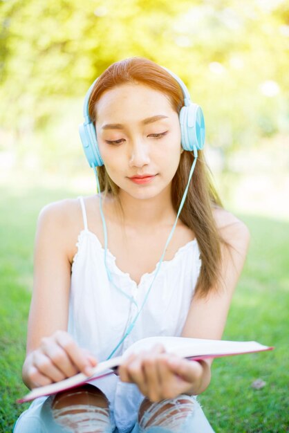 Libro di lettura della donna asiatica da solo nel parco il giorno di primavera. Relax e svago. Attività all'aperto e stile di vita in vacanza.