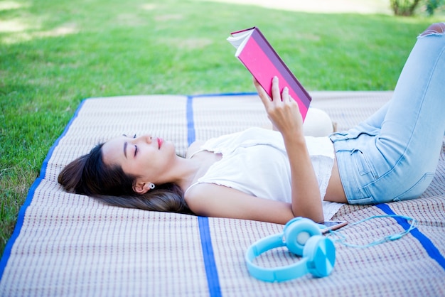 Libro di lettura della donna asiatica da solo nel parco il giorno di primavera. Relax e svago. Attività all'aperto e stile di vita in vacanza.