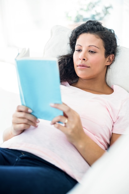 Libro di lettura della donna incinta sul sofà