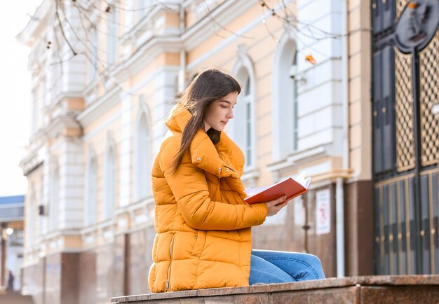 Libro di lettura della giovane donna all'aperto