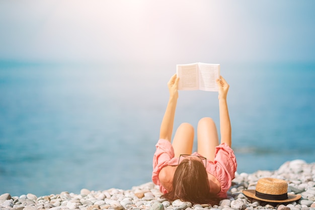 Libro di lettura della giovane donna durante la spiaggia bianca tropicale