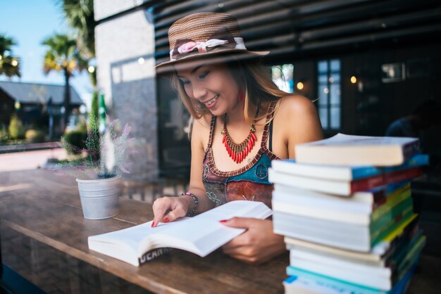 Libro di lettura della giovane donna e tazza di caffè fresca sulla tavola