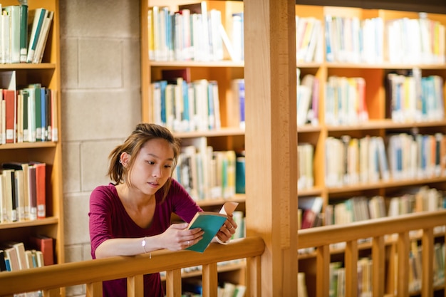 Libro di lettura della giovane donna in biblioteca