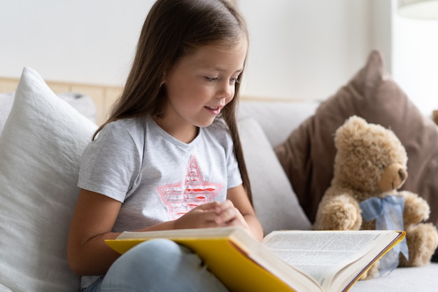 Libro di lettura della ragazza a casa. Istruzione a distanza, educazione a casa. Concetto di autoisolamento.