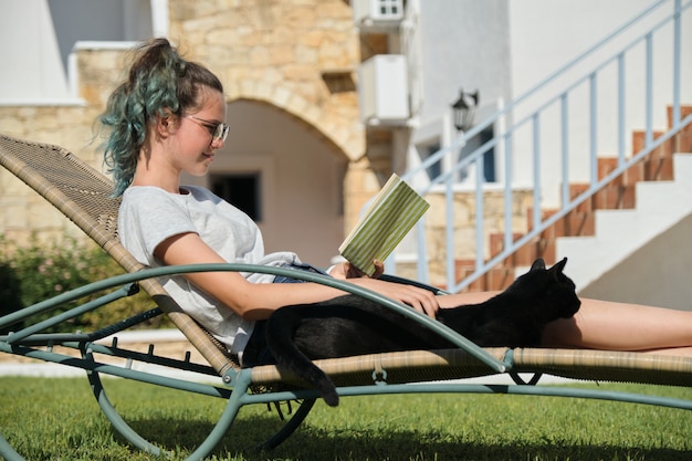 Libro di lettura della ragazza dell'adolescente con il gatto nero