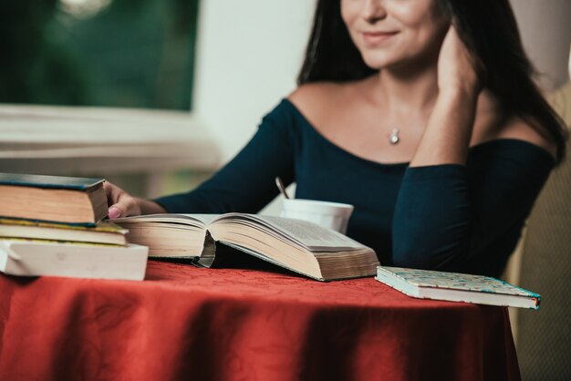 libro di lettura della ragazza mentre bevendo caffè al giorno soleggiato che si siede sul balcone.