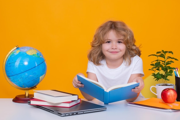 Libro di lettura per bambini in età scolare Ritorno a scuola Ragazzino divertente della scuola elementare con libro Ritratto di ragazzo della scuola isolato su sfondo giallo studio Istruzione