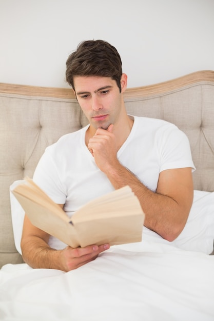 Libro di lettura rilassato dell&#39;uomo a letto