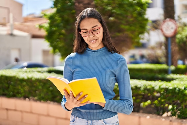 Libro di lettura sicuro sorridente della giovane donna afroamericana al parco