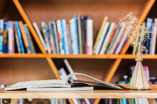 Libro di lettura sul tavolo di legno contro mensola.