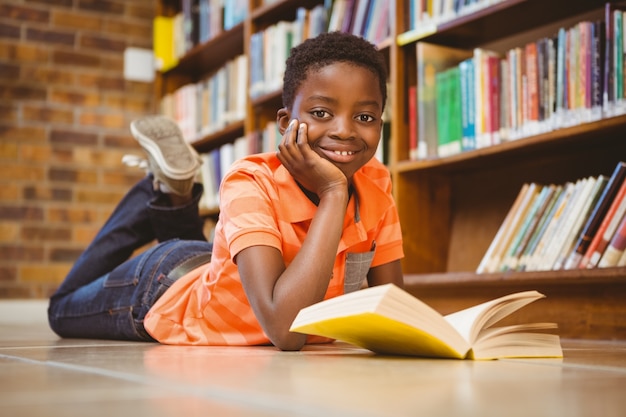 Libro di lettura sveglio del ragazzo in biblioteca