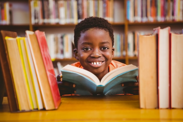 Libro di lettura sveglio del ragazzo in biblioteca