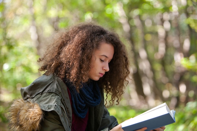 Libro di lettura teenager della ragazza nella sosta di autunno