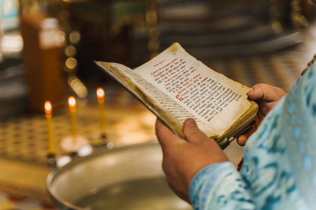 Libro sacro aperto nelle mani del sacerdote in chiesa