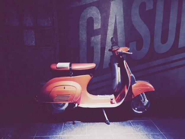Libro su scooter a motore arancione parcheggiato contro il muro