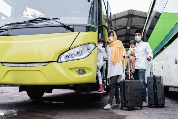 Liburan muslim Asia yang menyenangkan naik bus bersama keluarga memakai masker untuk mencegah penyebaran virus