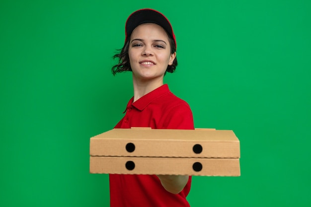 Lieta giovane bella donna delle consegne che porge scatole di pizza
