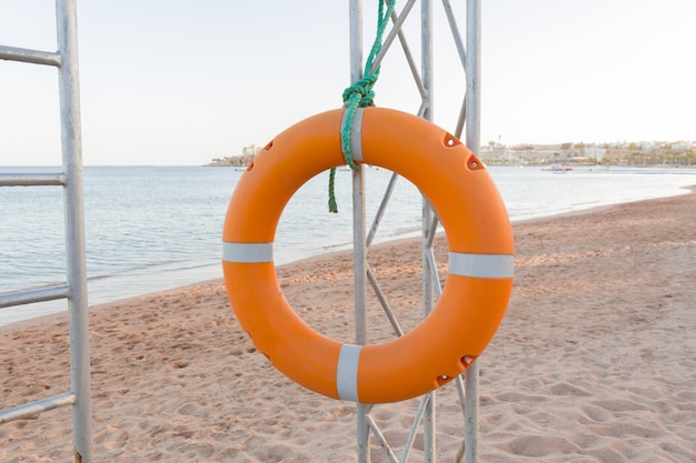 Lifebuoy arancio sulla torretta del bagnino su cielo blu e sulla spiaggia