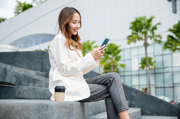 Lifestyle donna d'affari che sorride usando smartphone mobili nell'edificio degli uffici della città giovane