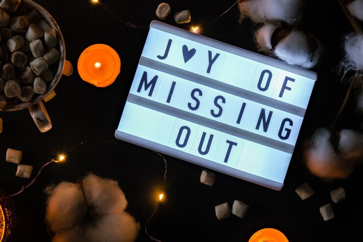 Lightbox con testo JOMO Joy of Missing Out. Il concetto di relax da informazioni e gadget. Vista dall'alto. Disposizione piatta. Tazza con cacao e marshmallow. Disintossicazione digitale
