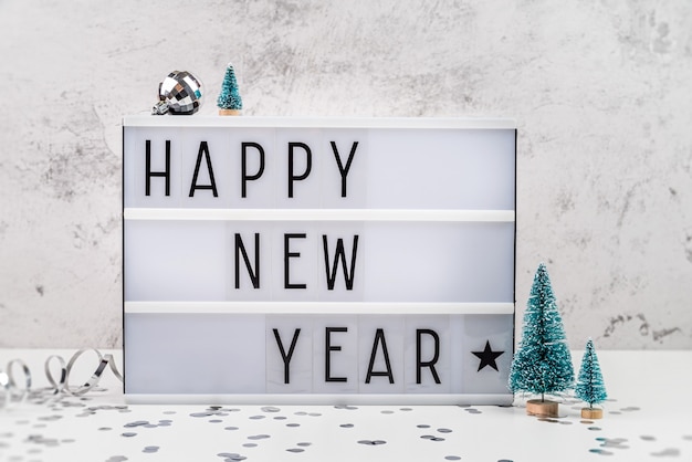 Lightbox lettera bianca con felice anno nuovo circondato con vista frontale di decorazioni di Natale