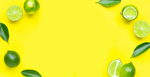 Lime fresche con foglie su sfondo giallo