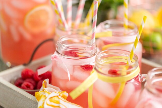 Limonata al lampone guarnita con limone fresco e lamponi in barattoli di vetro.